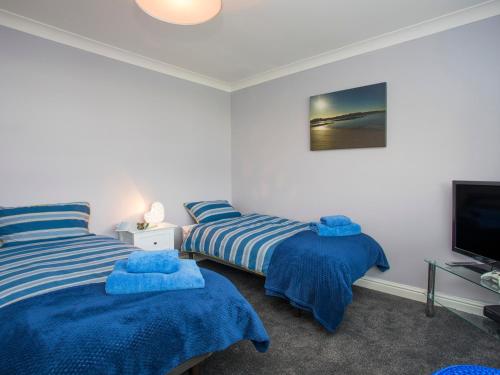 a bedroom with two beds and a television at Gadlys in Trearddur
