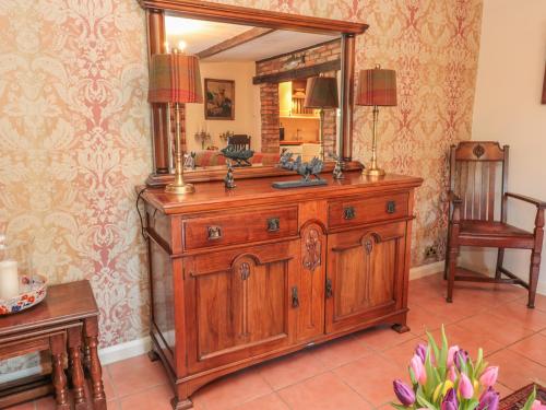 a wooden dresser with a mirror on top of it at Holly Cottage in Alnwick