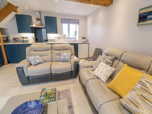 a living room with a couch and a kitchen at 7evern Porth Farm in Caersws