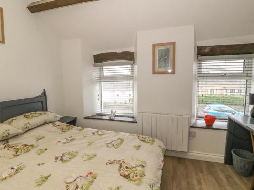 a bedroom with a bed and two windows at Ty Capel in Pwllheli