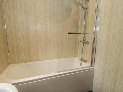 a white bath tub with a glass shower door at Arnant in Dolgellau