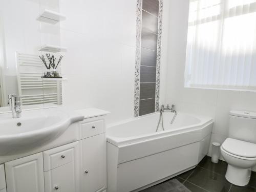 a white bathroom with a sink and a tub and a toilet at Southpoint in Bridlington