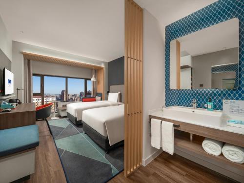 a hotel room with a bed and a sink and a mirror at Holiday Inn Express Changchun Jingyue by IHG in Changchun