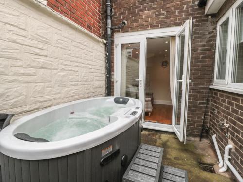 a jacuzzi tub sitting next to a brick building at Beach Cove View in Newbiggin-by-the-Sea