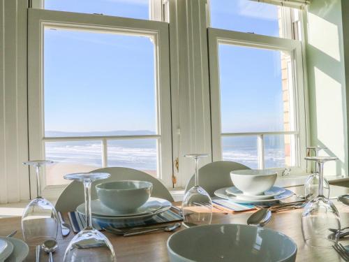 a table with glasses and dishes on it with two windows at Hartland View in Woolacombe
