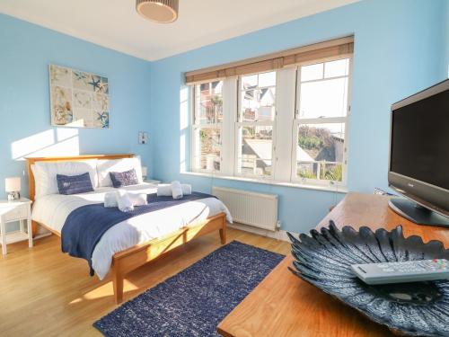 a blue bedroom with a bed and a tv at Hartland View in Woolacombe