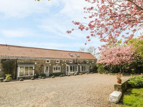 an old stone building with a driveway in front of it at Robin Cottage in Morpeth