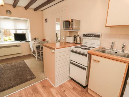 a kitchen with a sink and a stove top oven at Robin Cottage in Morpeth