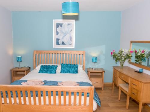 1 dormitorio con cama con almohadas azules y escritorio en Walnut Cottage, en Newton Abbot