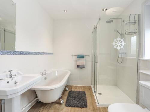 een badkamer met een bad, een wastafel en een douche bij Bwthyn Alberts in Trearddur