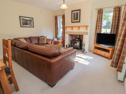 a living room with a brown leather couch and a fireplace at Gowanlea in Hexham