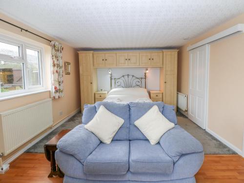 um quarto com um sofá azul em frente a uma cama em Bretton Mount Studio Flat em Eyam