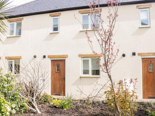 a white house with wooden doors at 9 Malthouse Court in Watchet