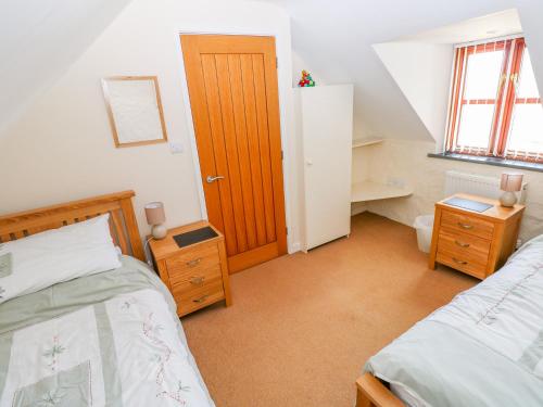1 dormitorio con 2 camas y puerta de madera en Maerdy Cwtch, en Haverfordwest