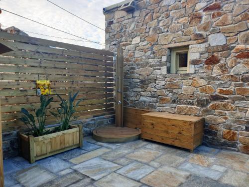 a patio with a stone wall and a bench at Anthoula's House in Psathi