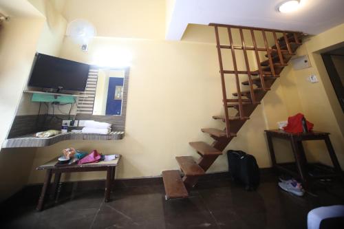 a living room with a staircase and a television at The Byke Heritage Resort - Matheran in Matheran
