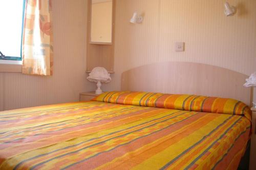 サン・レオーネにあるAkramar Villageのベッドルーム1室(カラフルな毛布付きのベッド1台付)
