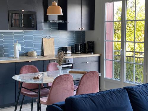 une cuisine avec une table et des chaises roses dans l'établissement Ambiance Seine, appartement surplombant la Seine -51 M2, Anémone-, à Thomery