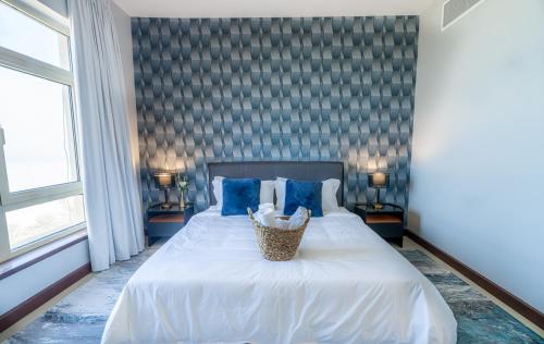 ein Schlafzimmer mit einem großen weißen Bett mit blauen Kissen in der Unterkunft Mabaat - Beach Tower - Building B - 251 in King Abdullah Economic City