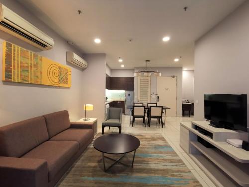 a living room with a couch and a dining room at Trinidad Suites Johor, Trademark Collection by Wyndham in Nusajaya