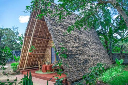 a small house with a large tree trunk at Charming Eco-Homestay near Kilimanjaro International Airport in Arusha