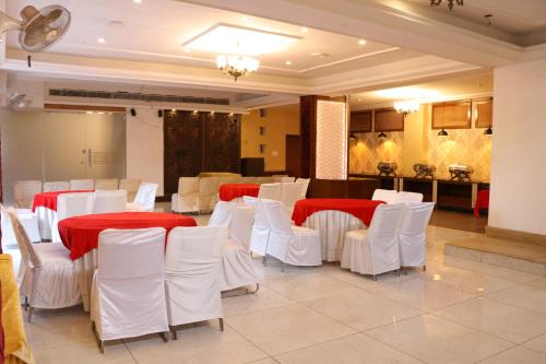 a banquet hall with red and white tables and chairs at Hotel Pushap Palace in Patiāla