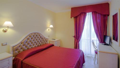 a bedroom with a red bed and a window at Loriana Park Hotel Sul Lago in Bolsena