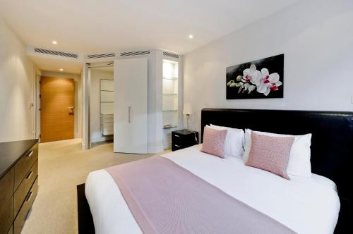 1 dormitorio con 1 cama blanca grande con almohadas rosas en Veeve - Chelsea Bridge Wharf en Londres