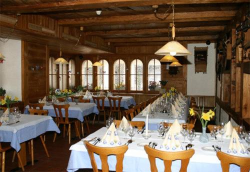 ein Esszimmer mit weißen Tischen, Stühlen und Fenstern in der Unterkunft Gasthof Krone in Luthern
