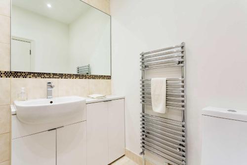 a white bathroom with a sink and a mirror at Veeve - Charming Hampstead Apartment in London