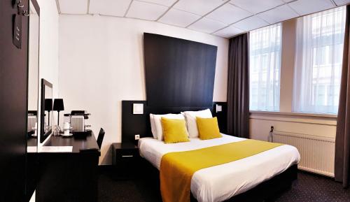 a hotel room with a large bed with yellow pillows at Hotel De Looier in Amsterdam