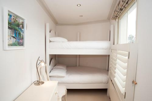 a small room with bunk beds and a window at Veeve - King's Road Roof Terrace in London