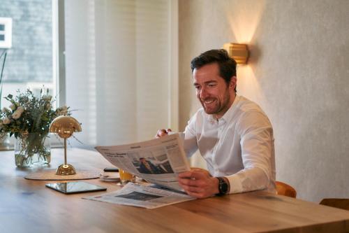 a man sitting at a table reading a newspaper at Hotel Engbert in Oelde