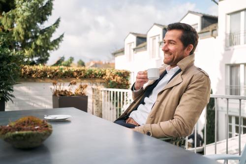 a man sitting at a table drinking a cup of coffee at Hotel Engbert in Oelde