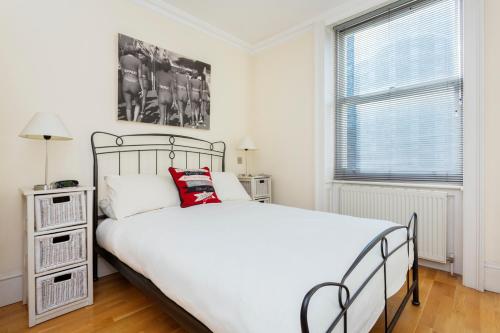 Un dormitorio con una gran cama blanca y una ventana en Veeve - Magnificent Marble Arch, en Londres