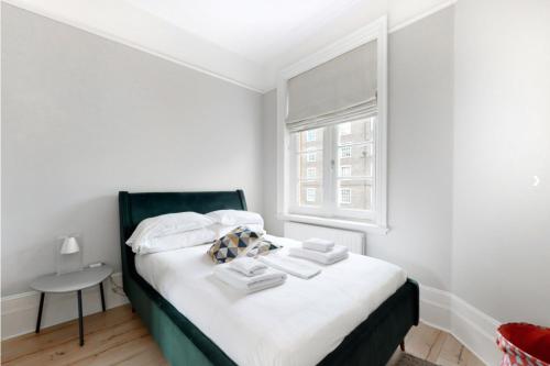 a bedroom with a bed with white sheets and a window at Modern 2 Bed Flat - The Black Dog Pub APT - 6 mins from Vauxhall station in London