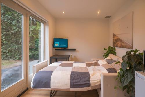 um quarto com uma cama, uma televisão e uma janela em Right Garden Suite in Villa near Centre and TUe em Eindhoven