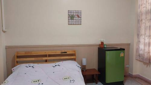 a bedroom with a bed and a green refrigerator at Sataya Apartment in Maha Sarakham
