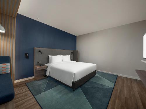 a bedroom with a white bed and a blue wall at Holiday Inn Express Changchun Jingyue by IHG in Changchun