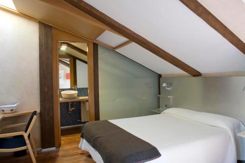 a bedroom with a white bed and a chair at Posada Real de Las Misas in Puebla de Sanabria