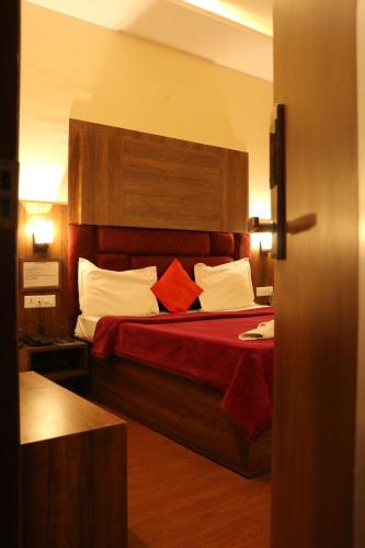 a bedroom with a bed with red sheets and white pillows at Hotel Pushap Palace in Patiāla