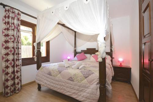 a bedroom with a canopy bed with pink pillows at Villa Llimona in Alcudia