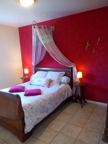 - une chambre dotée d'un lit avec un mur rouge dans l'établissement Les Plénitudes du Rivage, à Saint-Vincent-sur-Jard