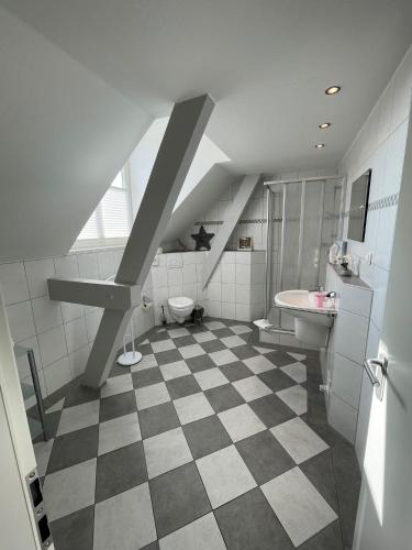an attic bathroom with a checkered floor and a sink at Kanal-Haus "Das Gästehaus direkt am Nord-Ostsee-Kanal" in Osterrönfeld