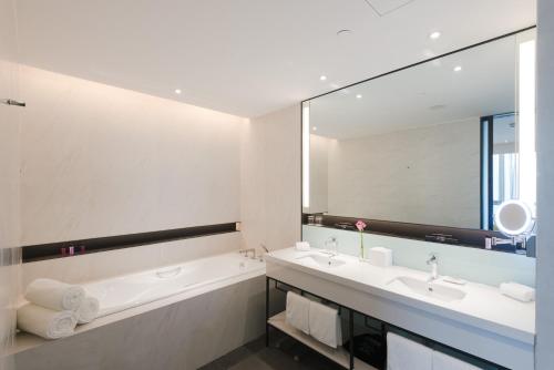 uma casa de banho com uma banheira, um lavatório e um espelho. em Innside By Melia Zhengzhou em Zhengzhou
