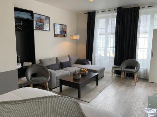 een woonkamer met een bank, stoelen en een tafel bij Studio Juno Beach in Bayeux