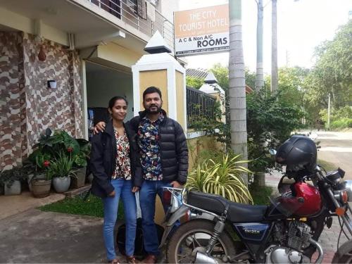 a man and a woman standing next to a motorcycle at The City Tourist Hotel in Anuradhapura