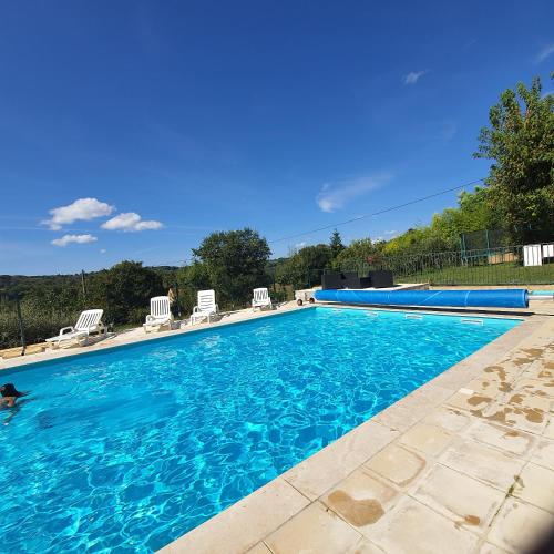 - une piscine avec de l'eau bleue et des chaises blanches dans l'établissement Chambres et table d'hôtes - Domaine de Bardenat, à Marquay