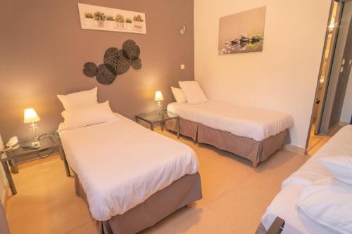 a room with two beds and two tables with lamps at Le President-Gare Nimes Pont Du Gard in Bellegarde