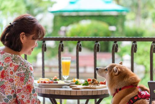 a woman and a dog sitting at a table with food at Promisedland Resort & Lagoon in Shoufeng